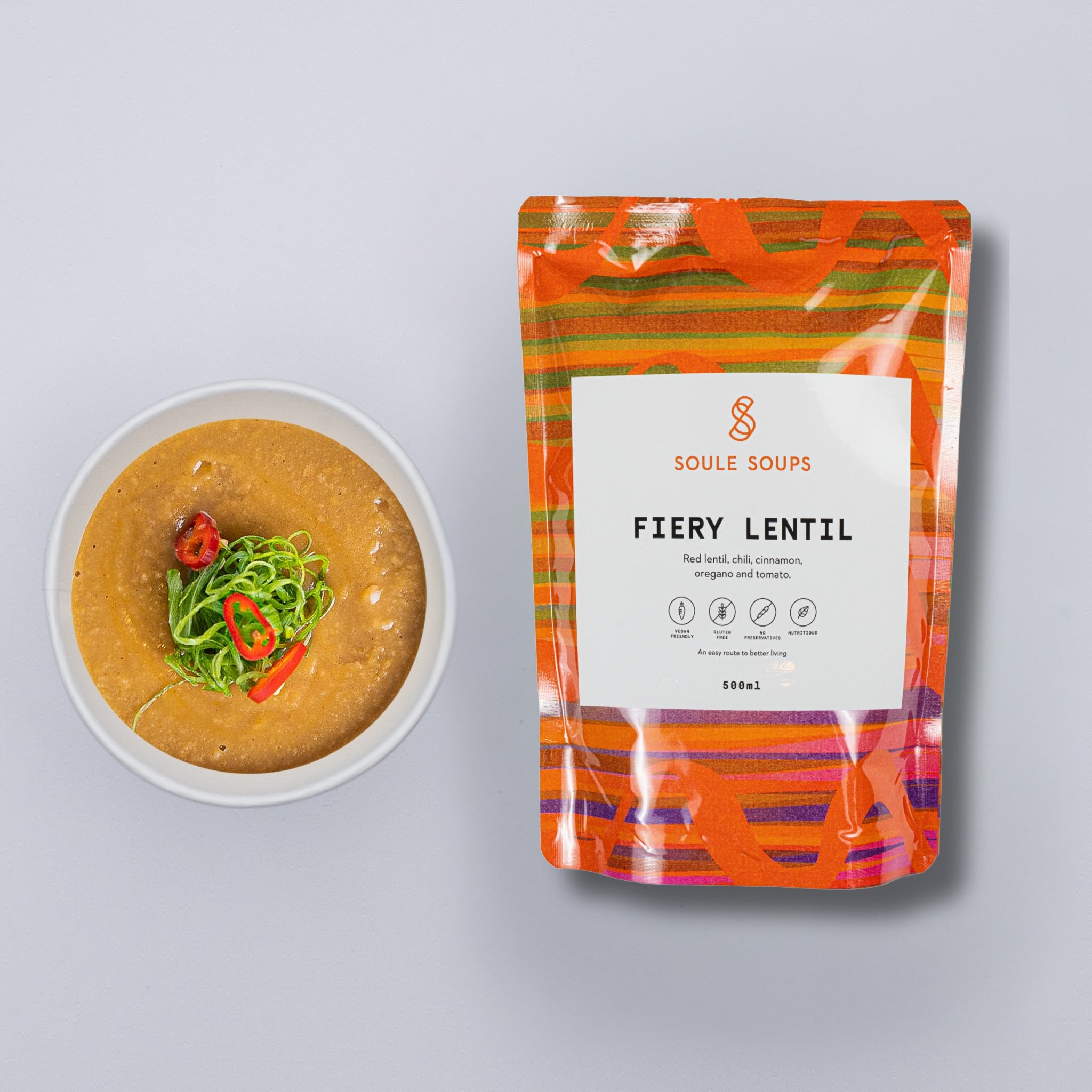 Packaged 'Fiery Lentil' soup from Soule Soups with a bowl of soup on a gray background