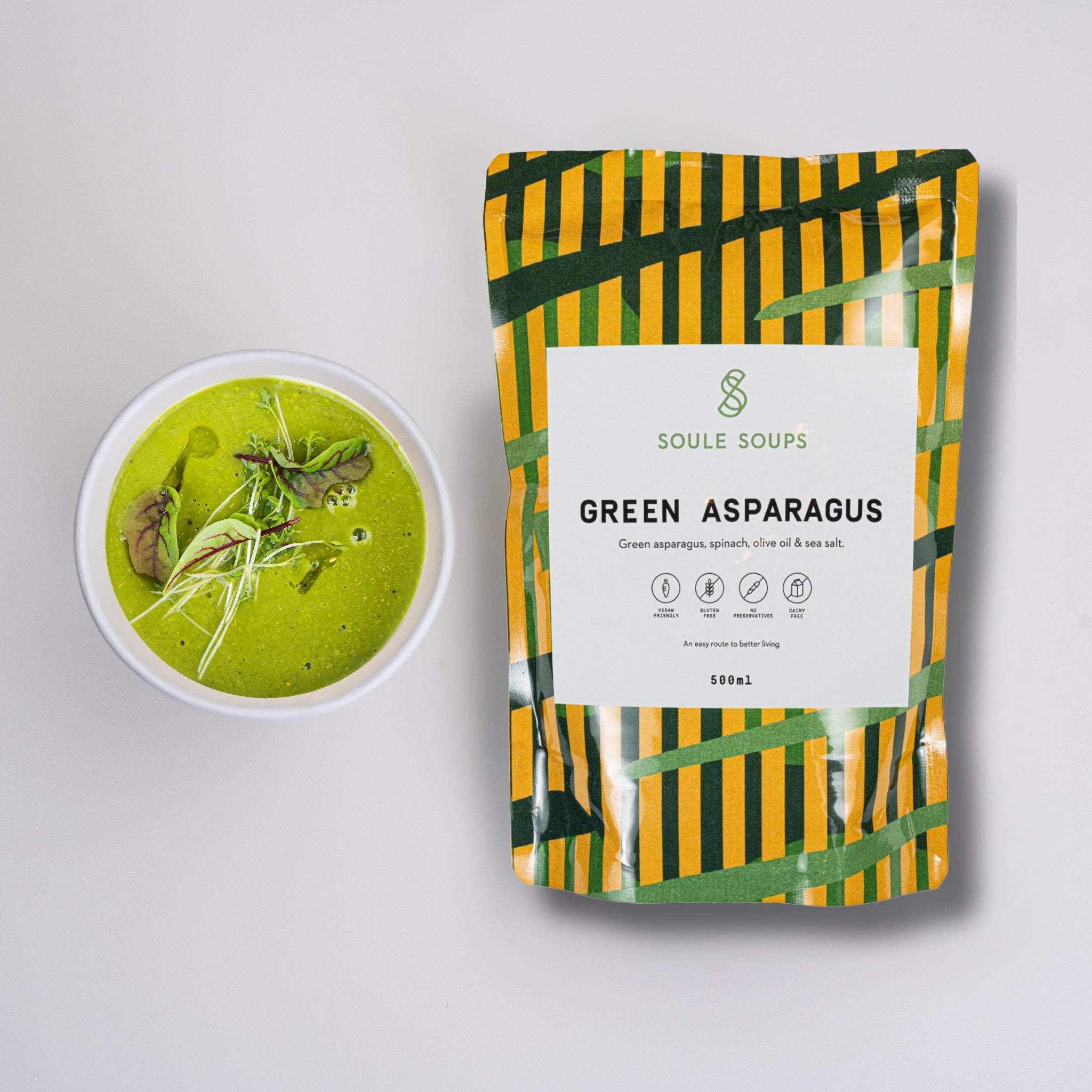 Soule Soups, Green asparagus soup in a bowl with a matchingSoule Soups packaging on a light gray background